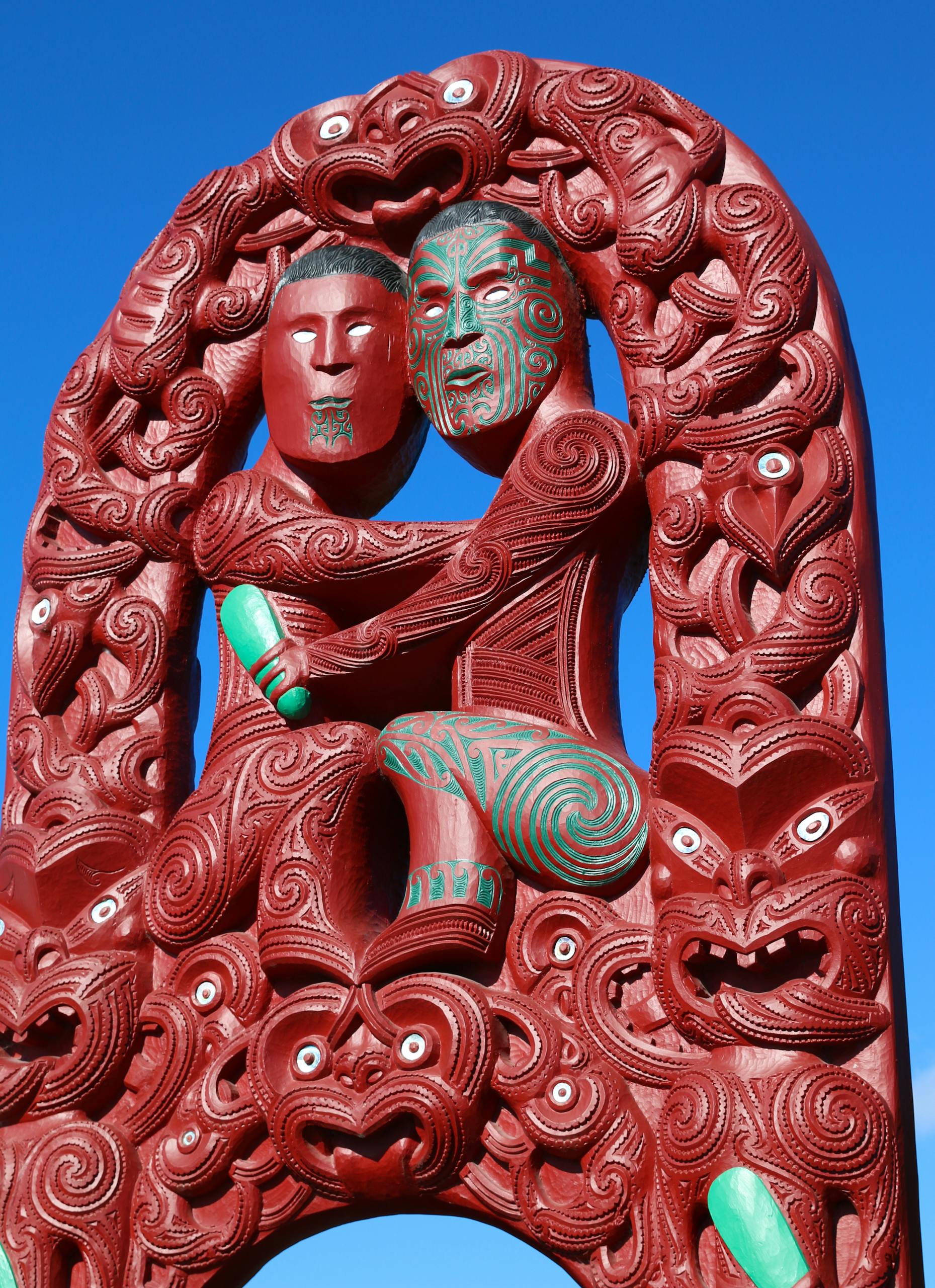 Detailed Maori carving in Rotorua against a clear blue sky, showcasing traditional artistry and cultural heritage.