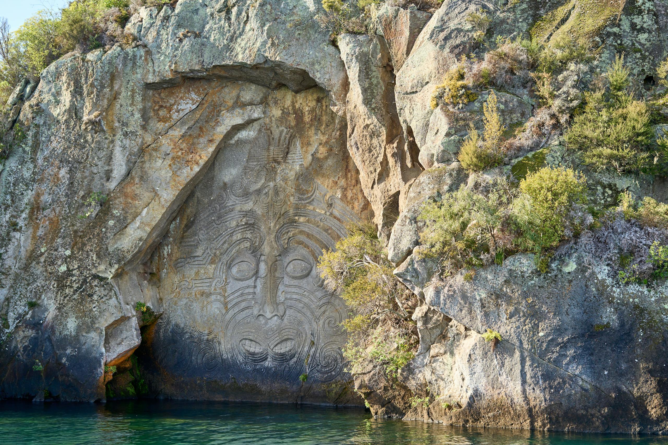 Stunning Maori rock carvings at Mine Bay on Lake Taupō, New Zealand.